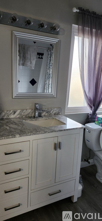 A bathroom with a marble countertop and a large mirror above it.