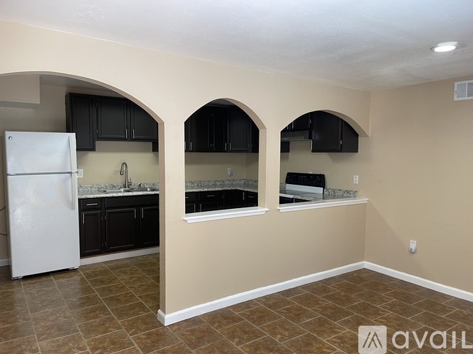 A kitchen with a white refrigerator and black cabinets.