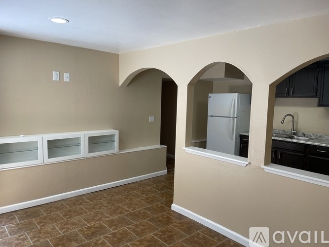 A kitchen area with a refrigerator, cabinets, and a countertop.
