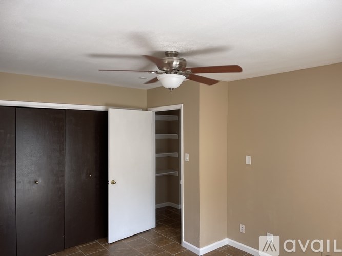 A room with a ceiling fan and a doorway leading to another room.