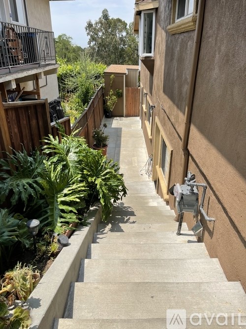 A set of stairs with a metal railing on the left side and a building on the right side.