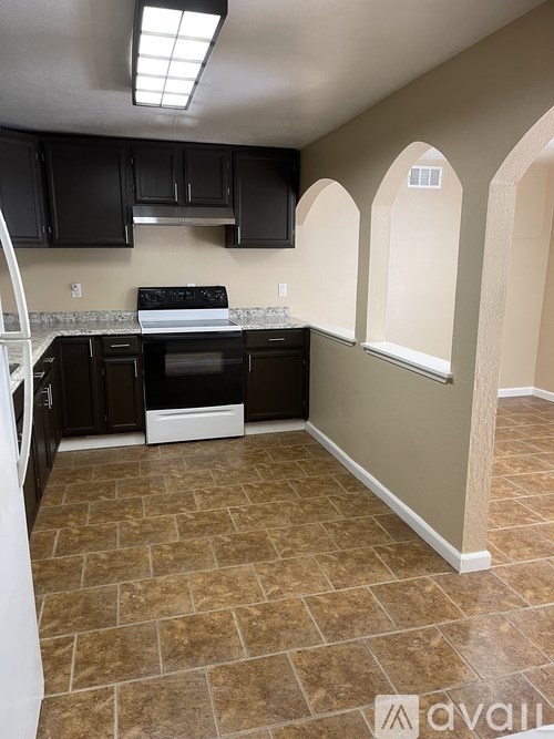 A kitchen with black cabinets and a tiled floor.