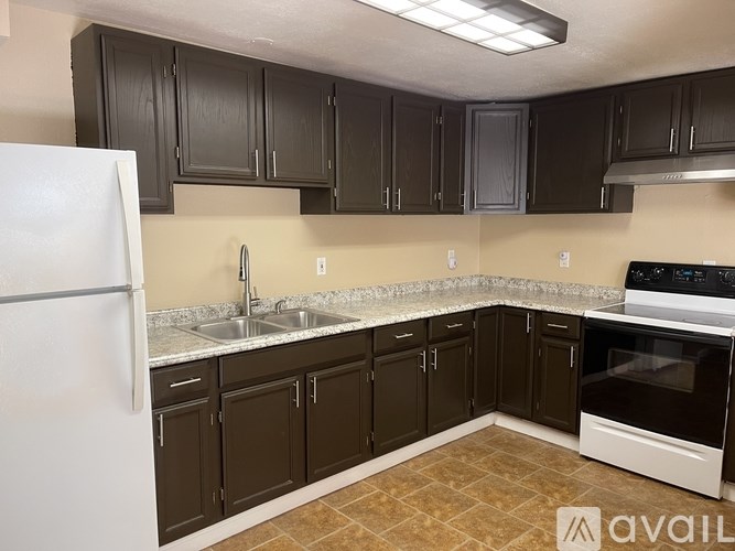 A kitchen with brown cabinets and a white refrigerator.