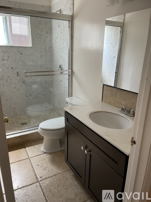 A bathroom with a toilet, sink, and shower.