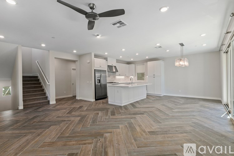 A spacious kitchen with a wooden floor and a ceiling fan.
