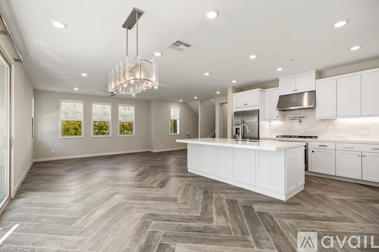 A modern kitchen with a large island and a chandelier.