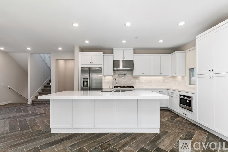 A modern kitchen with white cabinets and a wooden floor.