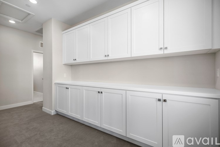 A row of white cabinets are on a wall in a room.