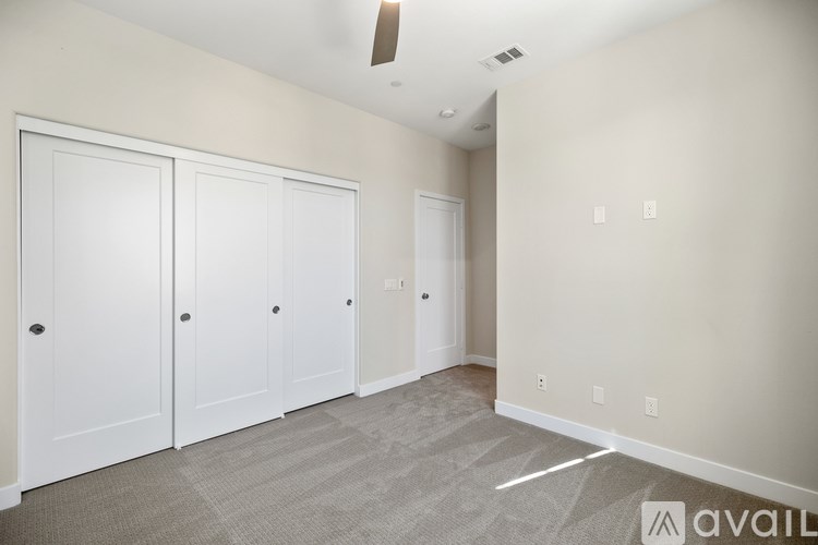 A room with a carpeted floor and a ceiling fan.