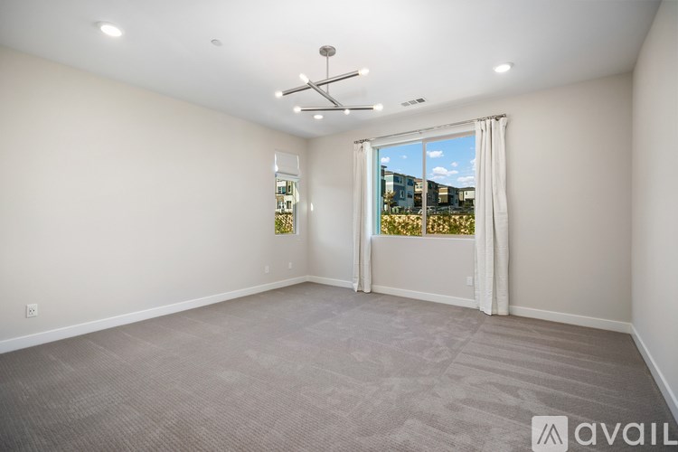 A spacious room with a carpeted floor and a ceiling fan.