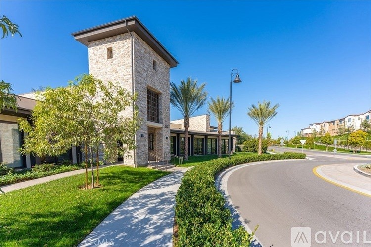 A modern house with a stone tower and a curved driveway.