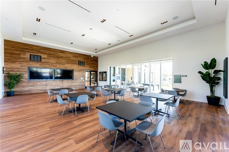 A spacious room with a long table and chairs, a television, and a wooden wall.