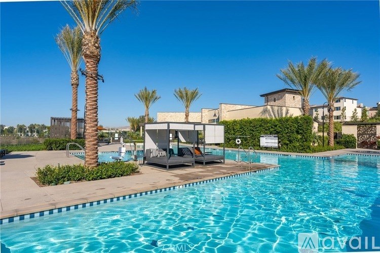 A pool area with a sun lounger and palm trees.