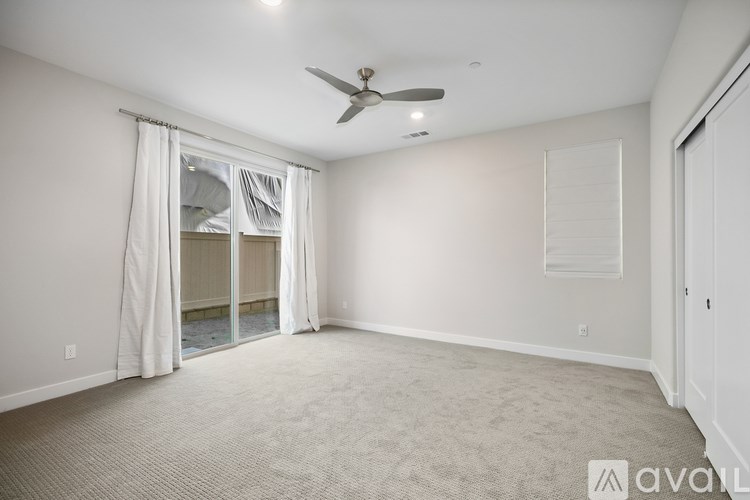 A room with a ceiling fan and carpeted floor.