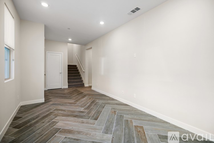 A hallway with wooden flooring and a staircase.