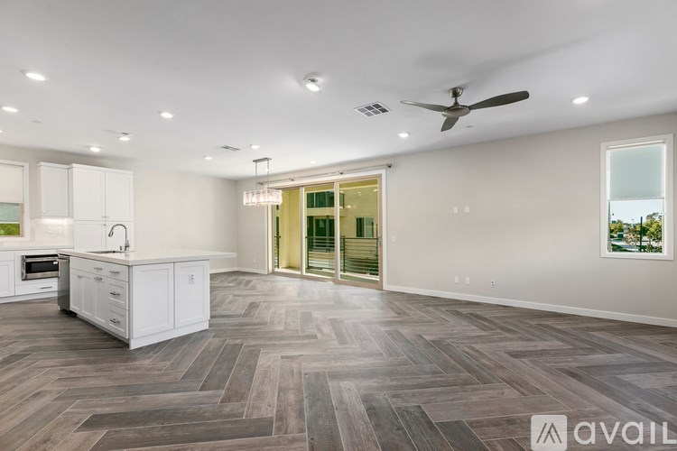 A spacious kitchen with a fan and a view of the outdoors through a glass door.