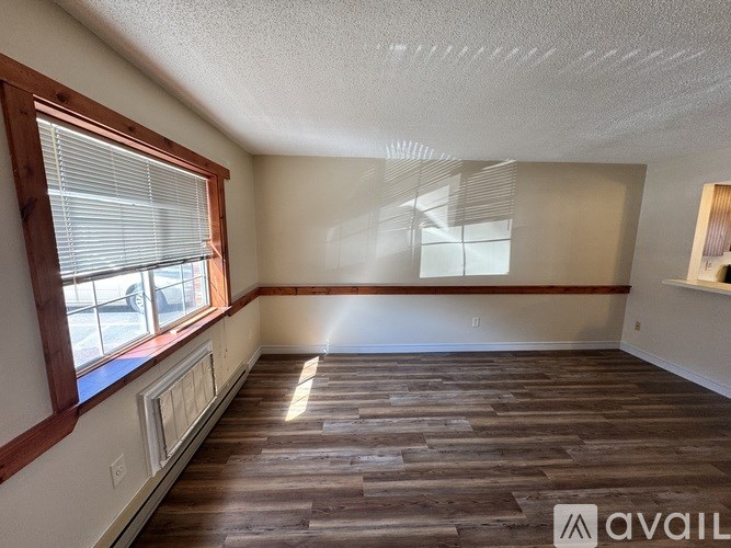 A room with wooden flooring and a window with blinds.