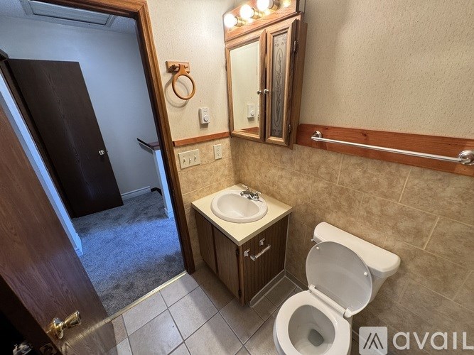 A bathroom with a toilet, sink, and mirror.