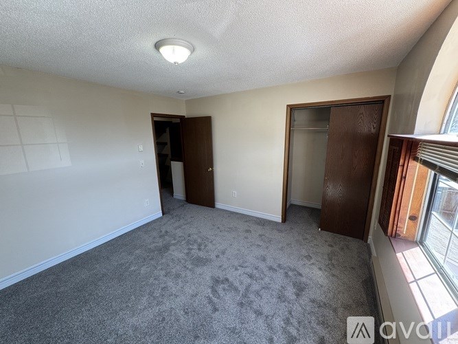A room with a carpeted floor and two doors.