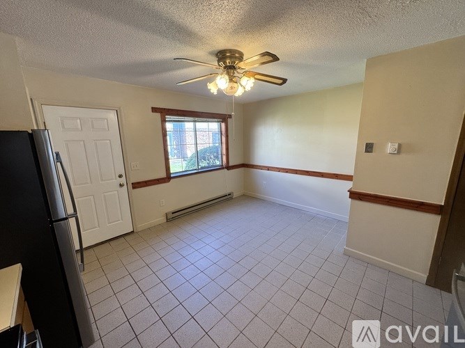 A kitchen with a black fridge and a ceiling fan.