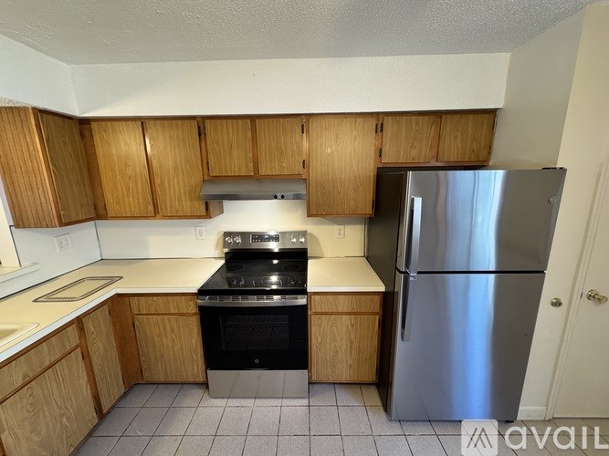 A kitchen with wooden cabinets and a stainless steel refrigerator.