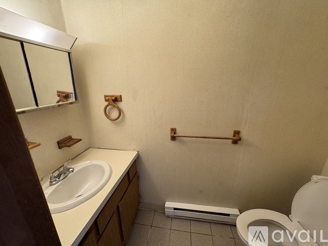 A bathroom with a toilet, sink, and mirror.