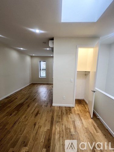 A room with wooden flooring and a skylight.