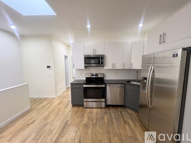 A modern kitchen with stainless steel appliances and wooden flooring.