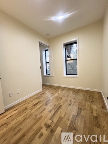 A room with wooden flooring and a window with a view of trees.