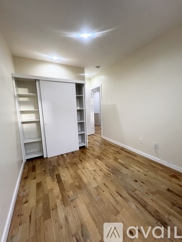 A room with a white door and wooden flooring.