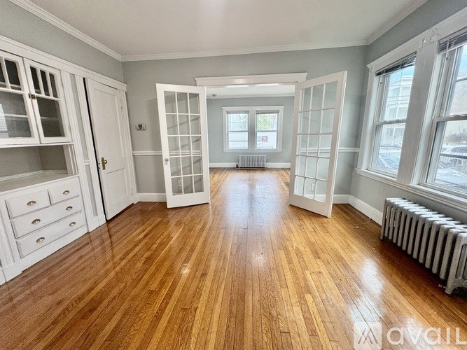 A room with wooden floors and white cabinetry is available for rent.