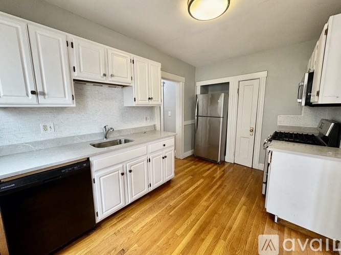 A kitchen with white cabinets and a wooden floor.