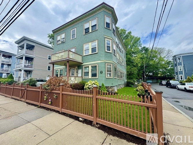 A green two-story house with a brown fence in front.