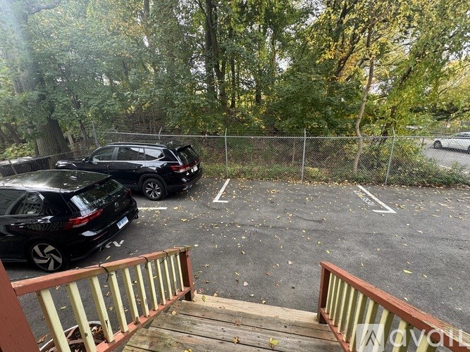 A black car is parked in a lot with a wooden deck in front.