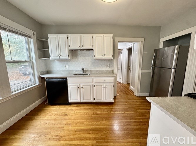A kitchen with wooden floors and white cabinets.
