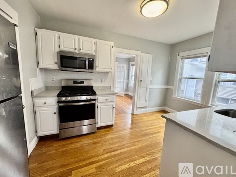 A kitchen with white cabinets and a stainless steel refrigerator.