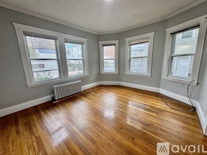 A room with wooden floors and three windows.