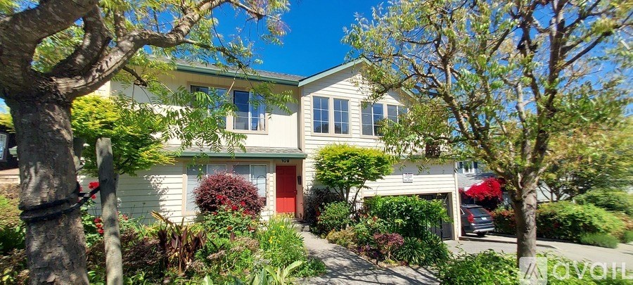 A house with a red door is surrounded by greenery.