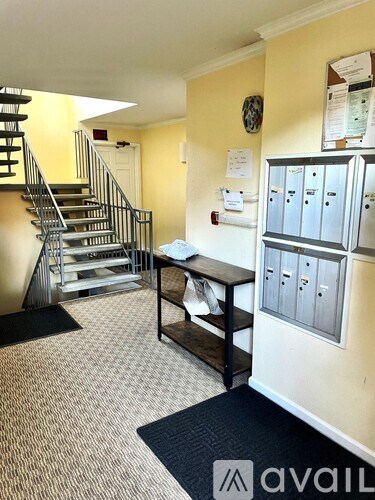 A hallway with a staircase and a desk with a chair.
