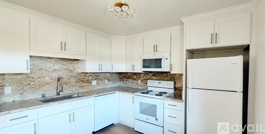 A kitchen with white cabinets and appliances.