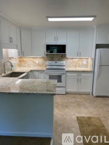 A kitchen with granite countertops and white cabinets.