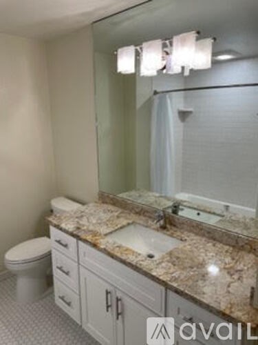 A bathroom with granite countertops and a white toilet.