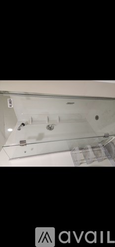 A bathroom with a glass shower door and a white wall.
