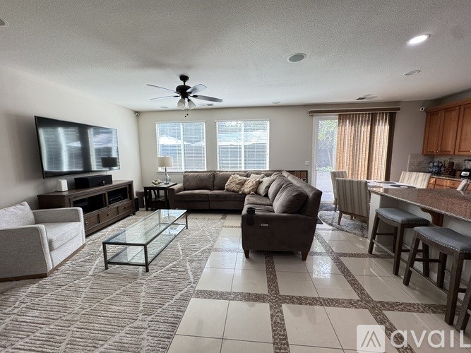 A spacious living room with a television, couches, and a bar area.