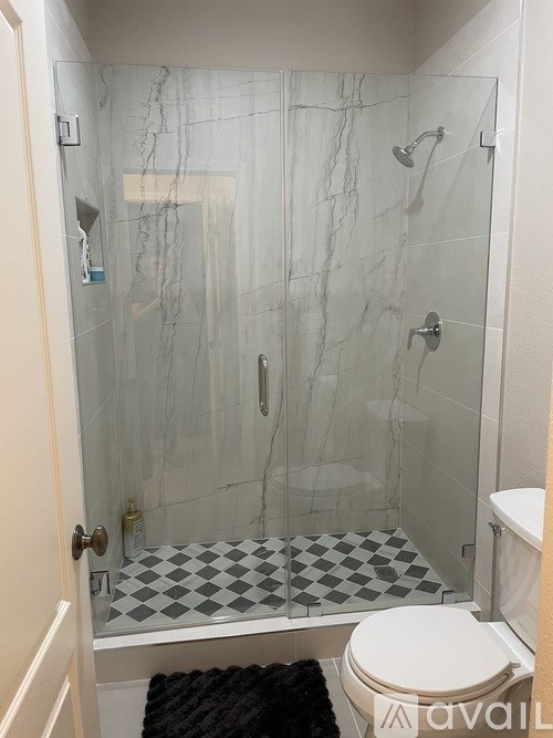 A bathroom with a marble shower and a checkered floor.