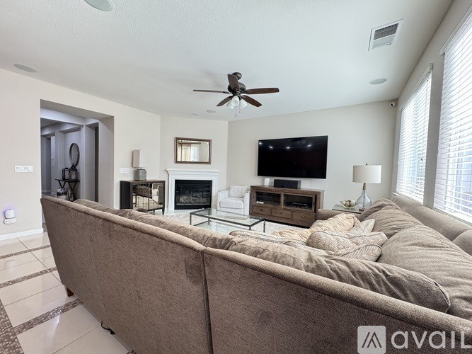 A living room with a brown couch and a flat screen TV mounted on the wall.