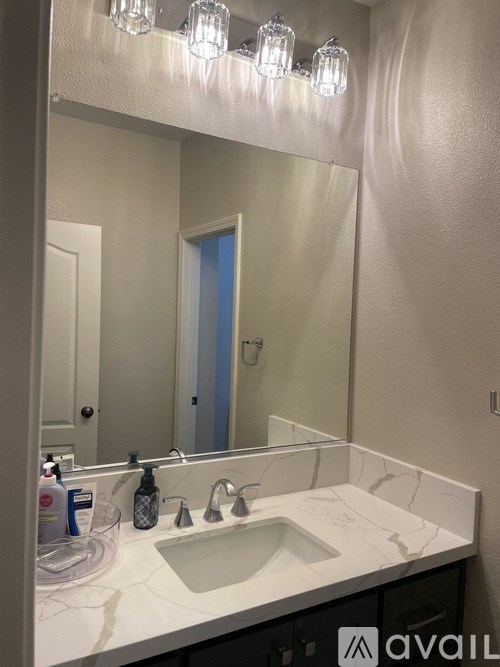 A bathroom with a sink, mirror, and lights.