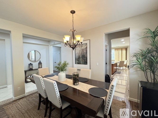 A dining room with a table set for six and a chandelier hanging from the ceiling.