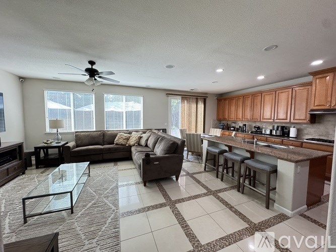 A spacious living room with a kitchen area in the background.