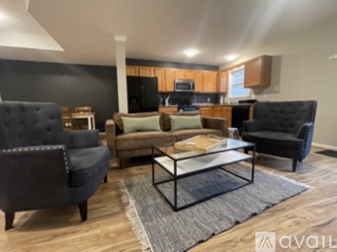 A living room with a black couch, a black chair, and a glass coffee table.